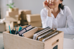 close-up view of box with office supplies and businesswoman sitting behind